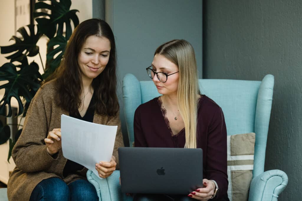 Zwei Mitarbeiterinnen mit Laptop und Zettel